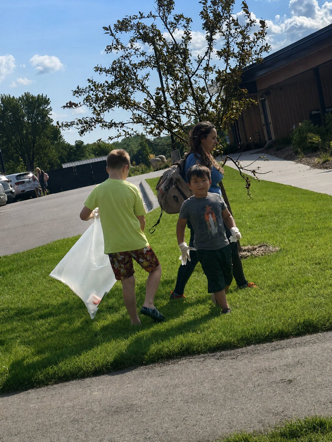 Two children and an adult volunteer taking part in a Moore Lake Park cleanup.