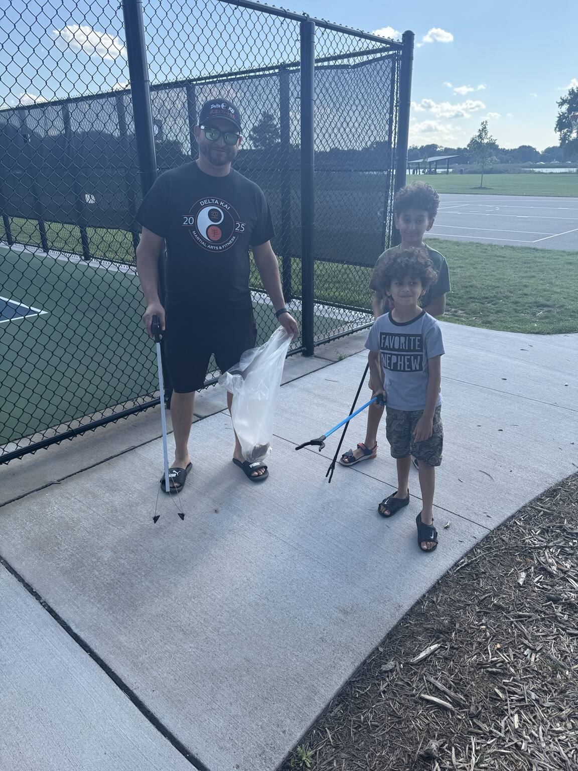 Delta Kai volunteers using litter grabbers during a Moore Lake Park cleanup.
