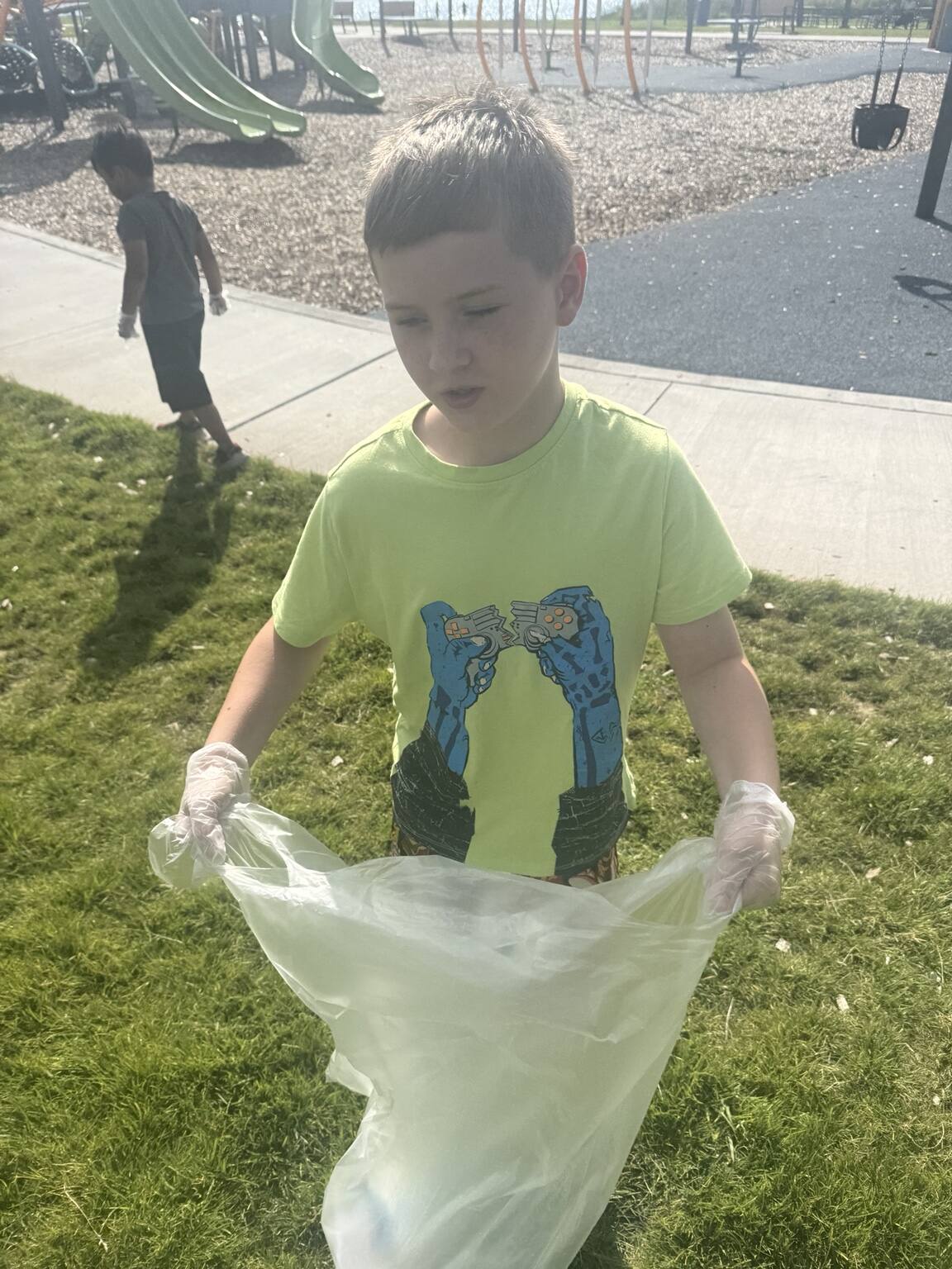 A young Community Warrior holding a cleanup bag at Moore Lake Park.
